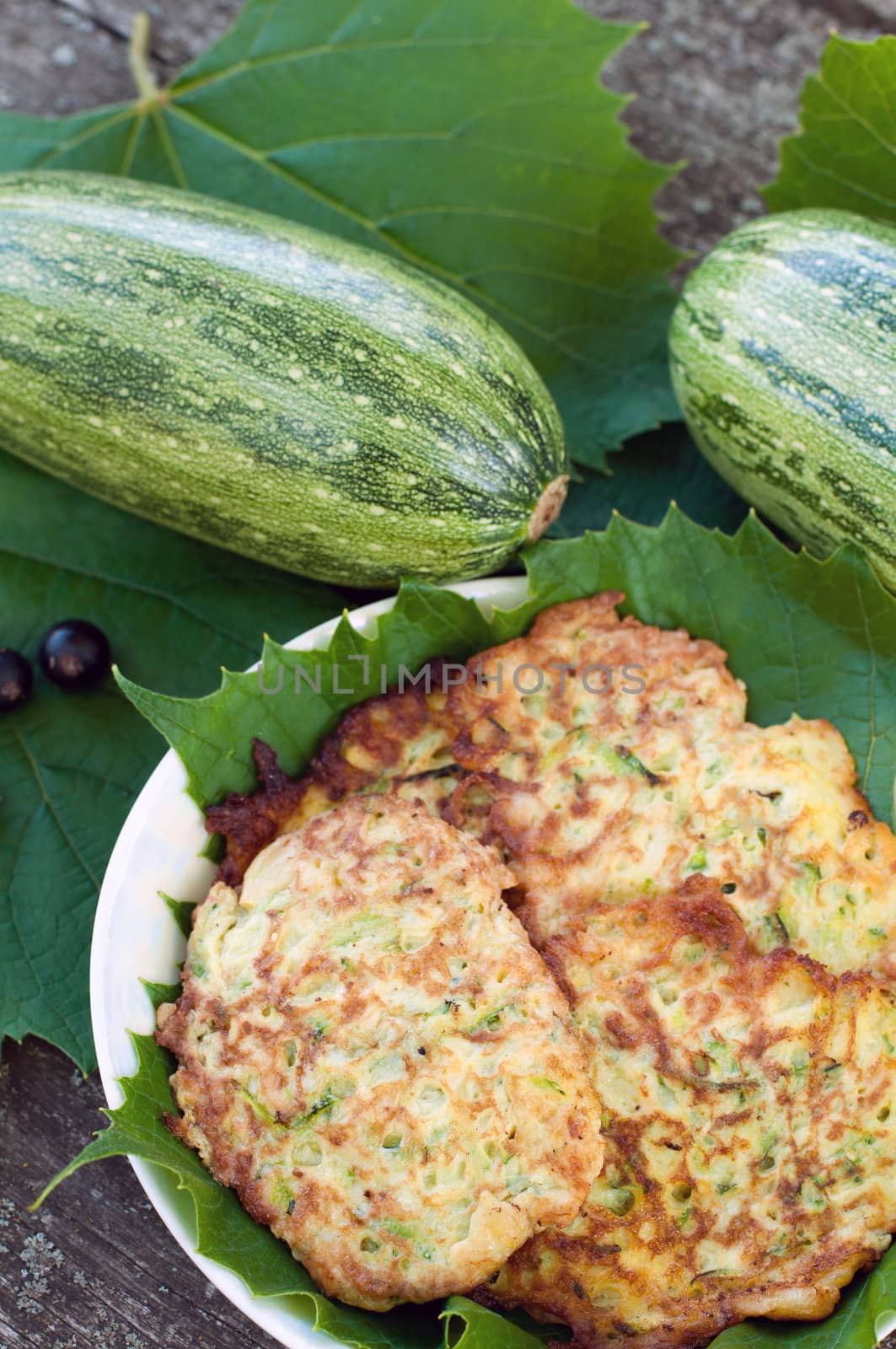 Pancakes with fresh zucchini on grape leaves by olgavolodina