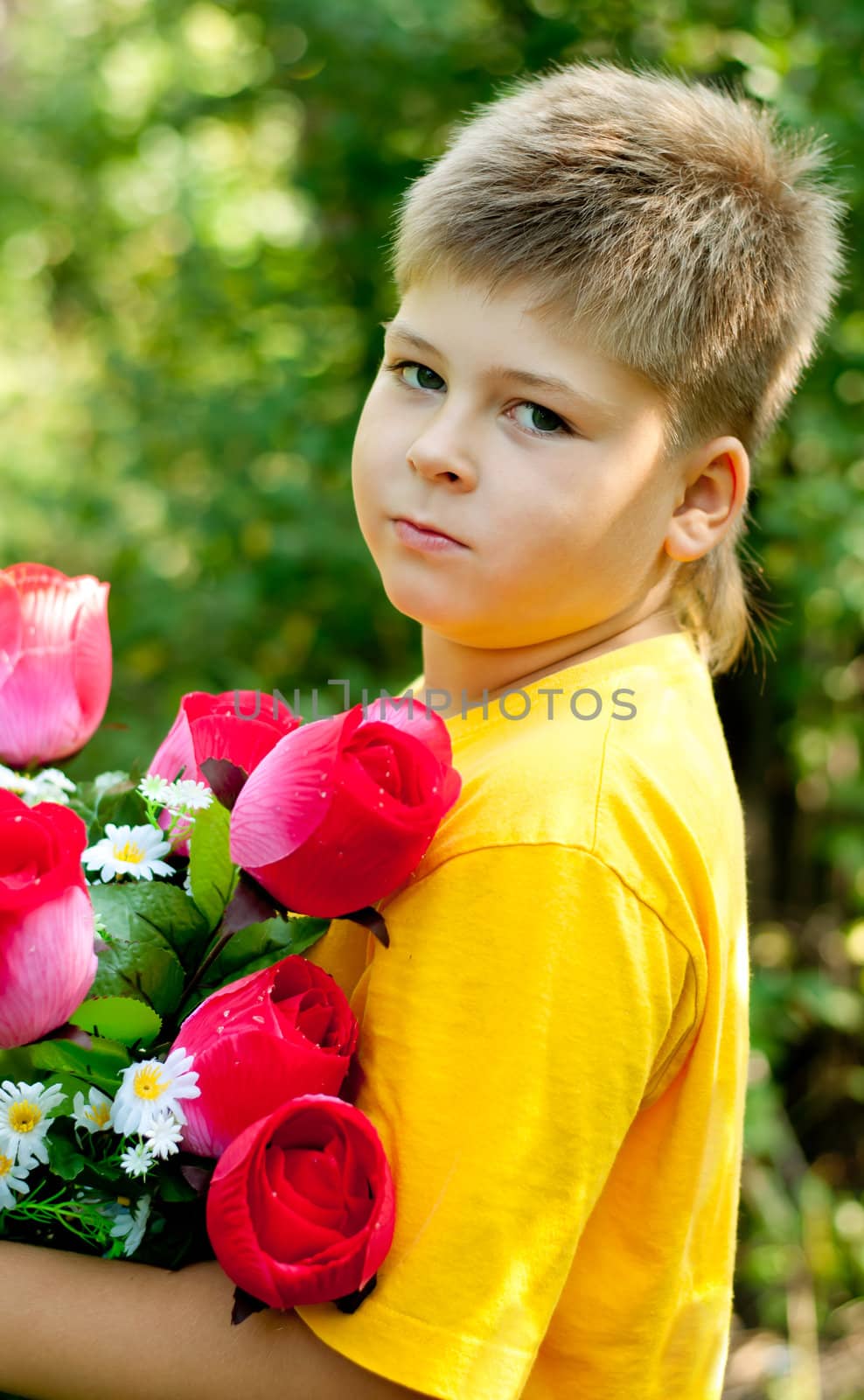 A boy with a bouquet of artificial flowers in summer park