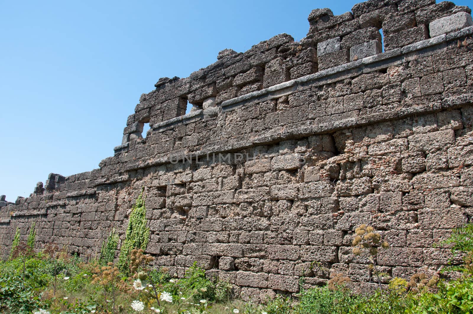 The ruins of the ancient city wall in Side, Turkey by olgavolodina