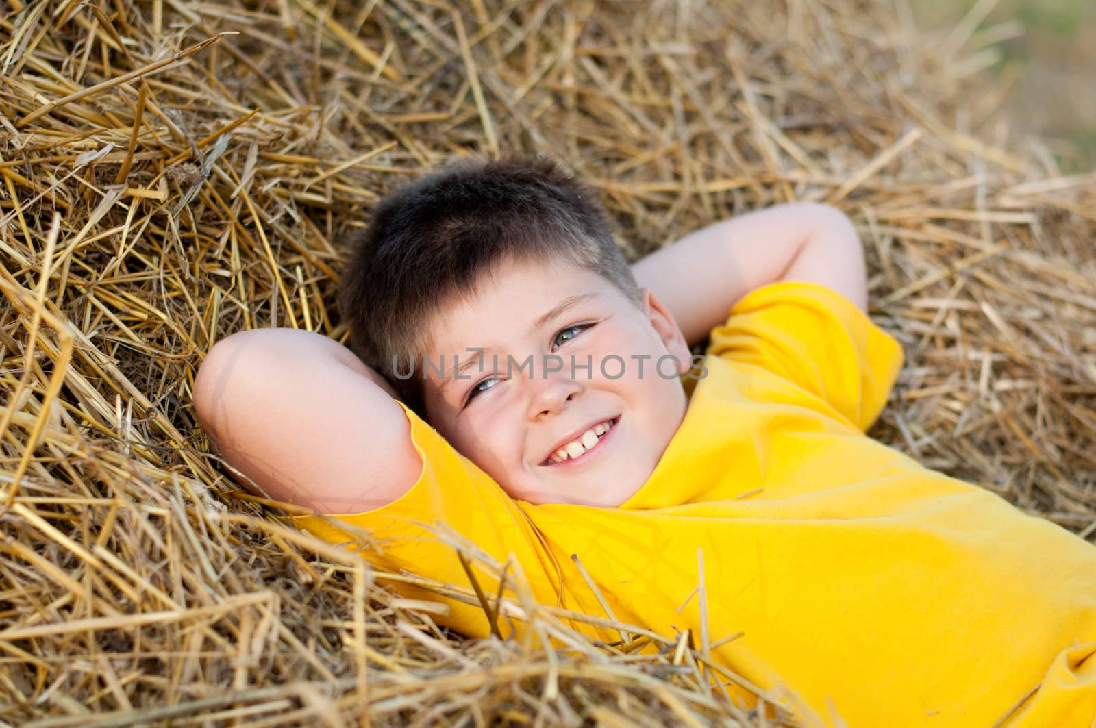 Boy lying on the straw by olgavolodina