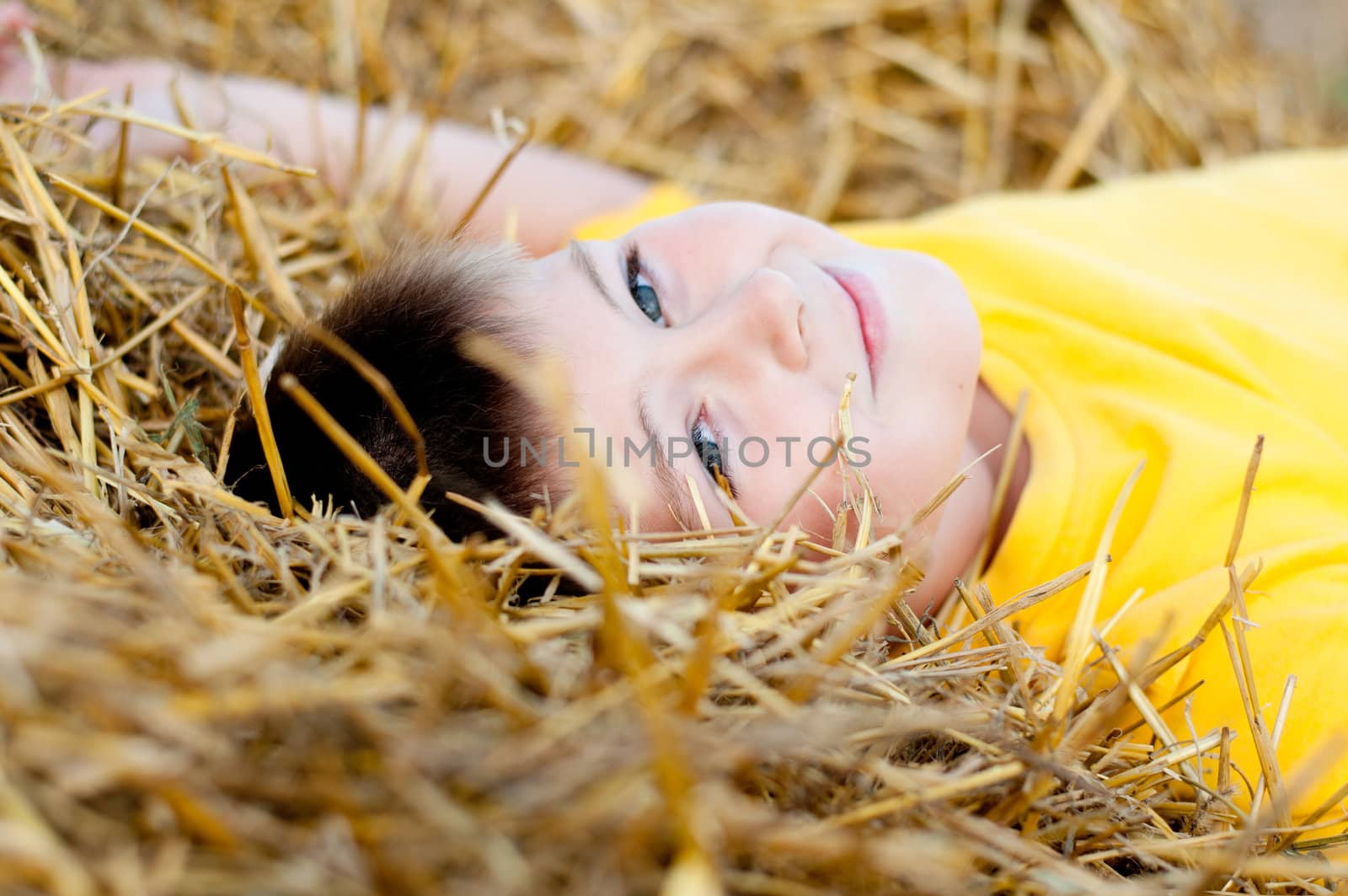 Boy lying on the straw by olgavolodina