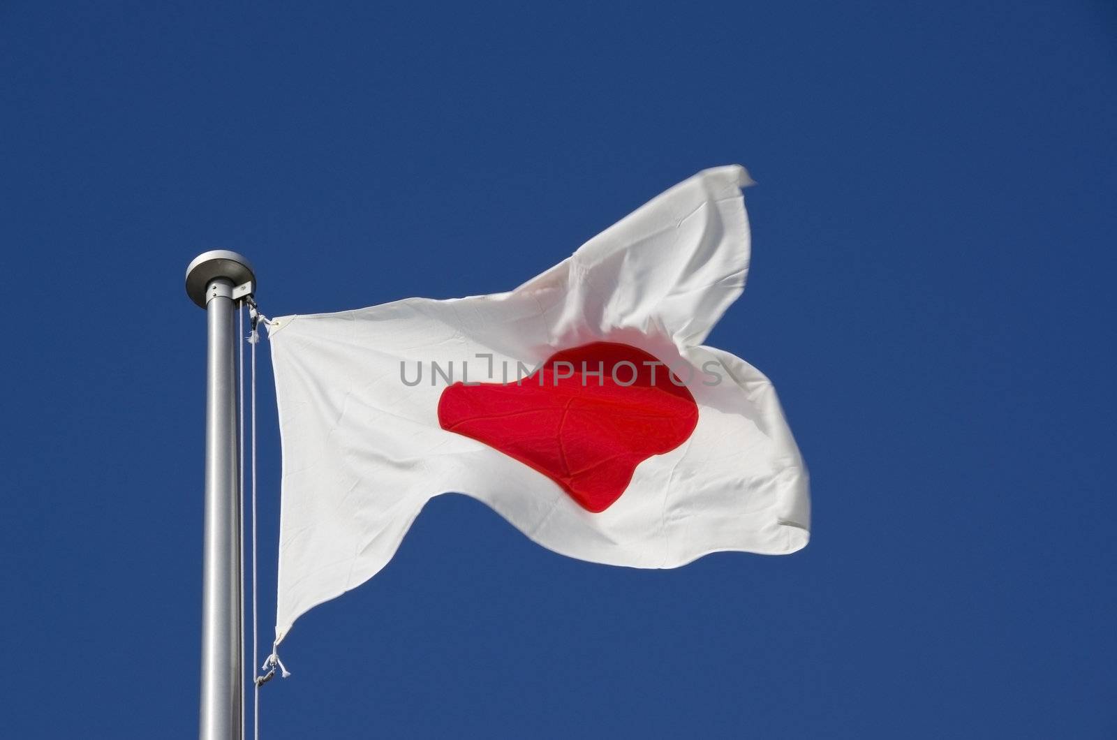 Japanese flag on flag pole against a blue sky