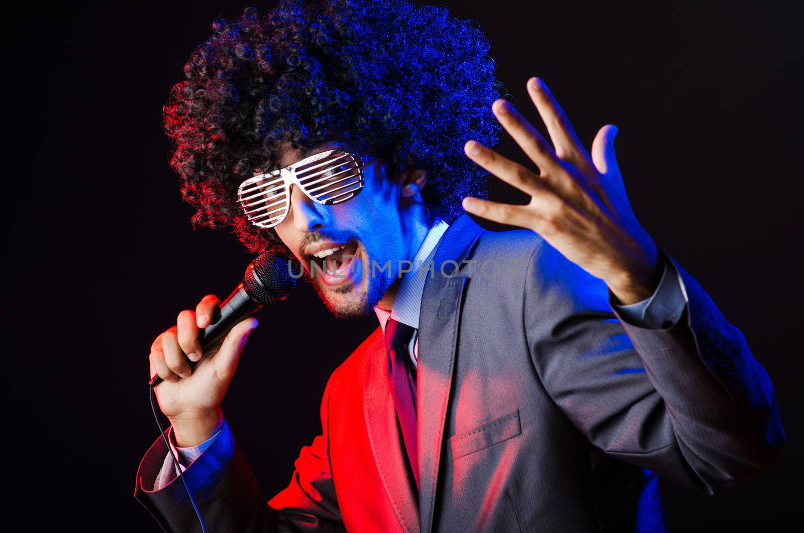 Young singer in afro wig singing at disco