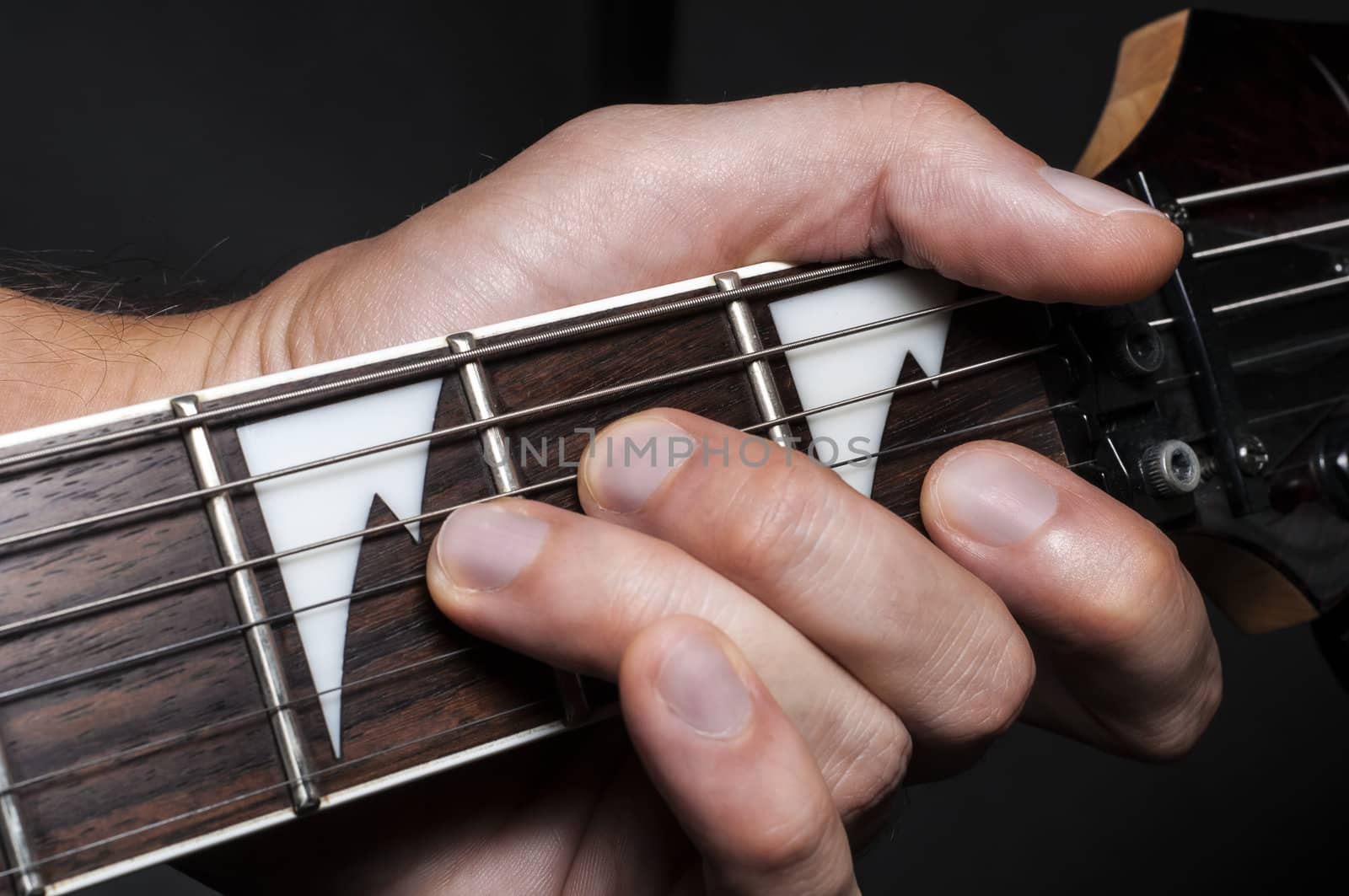 Close up shot of a man with his fingers on the frets of a guitar