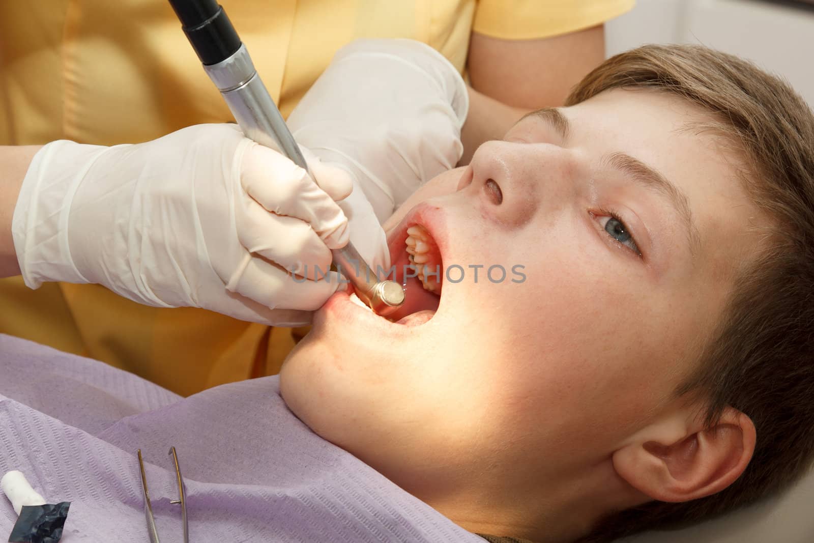 dentist treats the boy's teeth with a drill