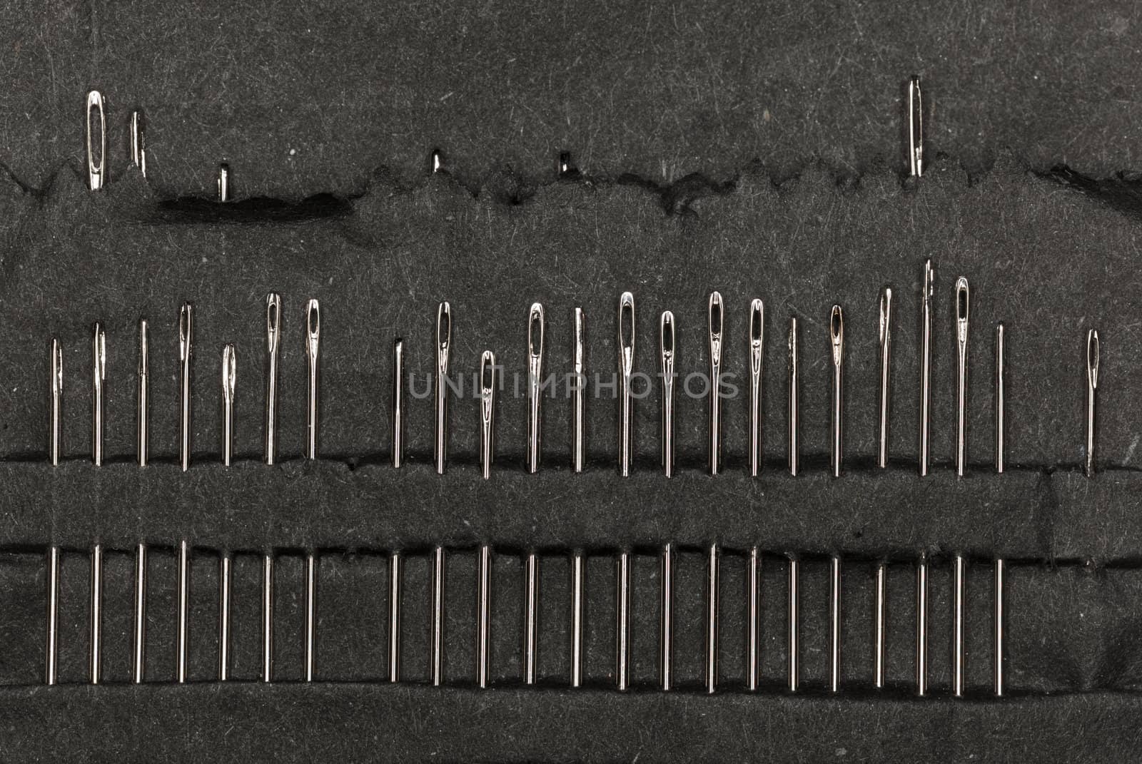 Macro image of a row of sewing needles in black paper case