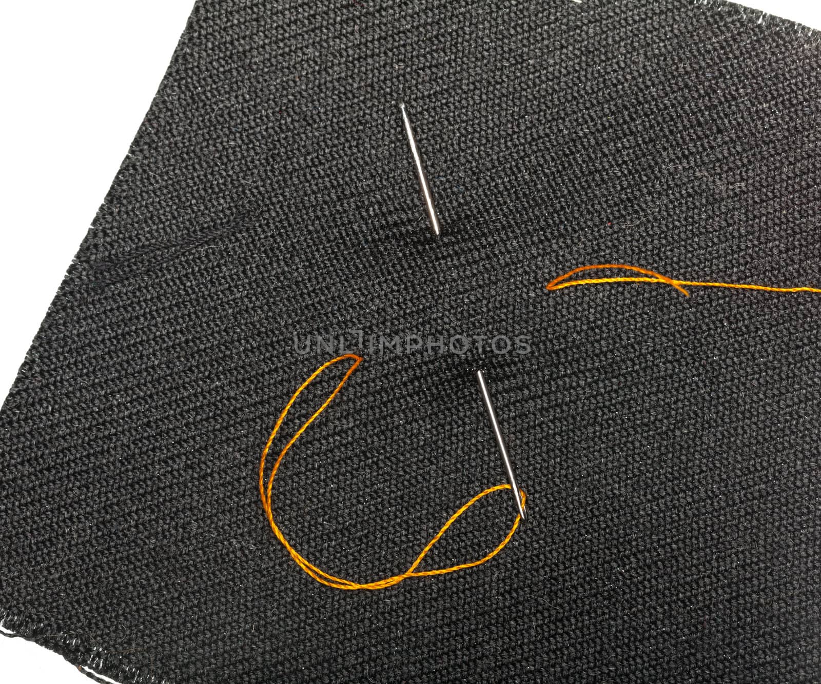 Orange thread and needle in black cloth by steheap