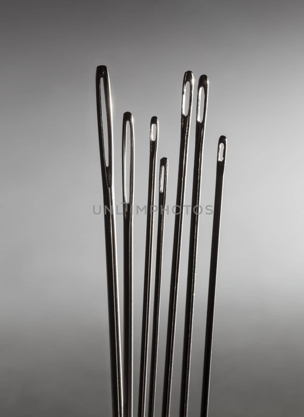 Row of sewing embroidery needles against grey background