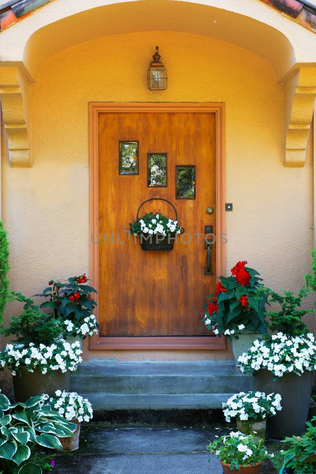 Weathered wood stained home door with three windows and flowers