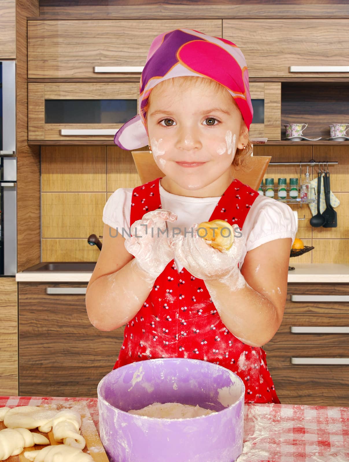 little girl make rolls in kitchen