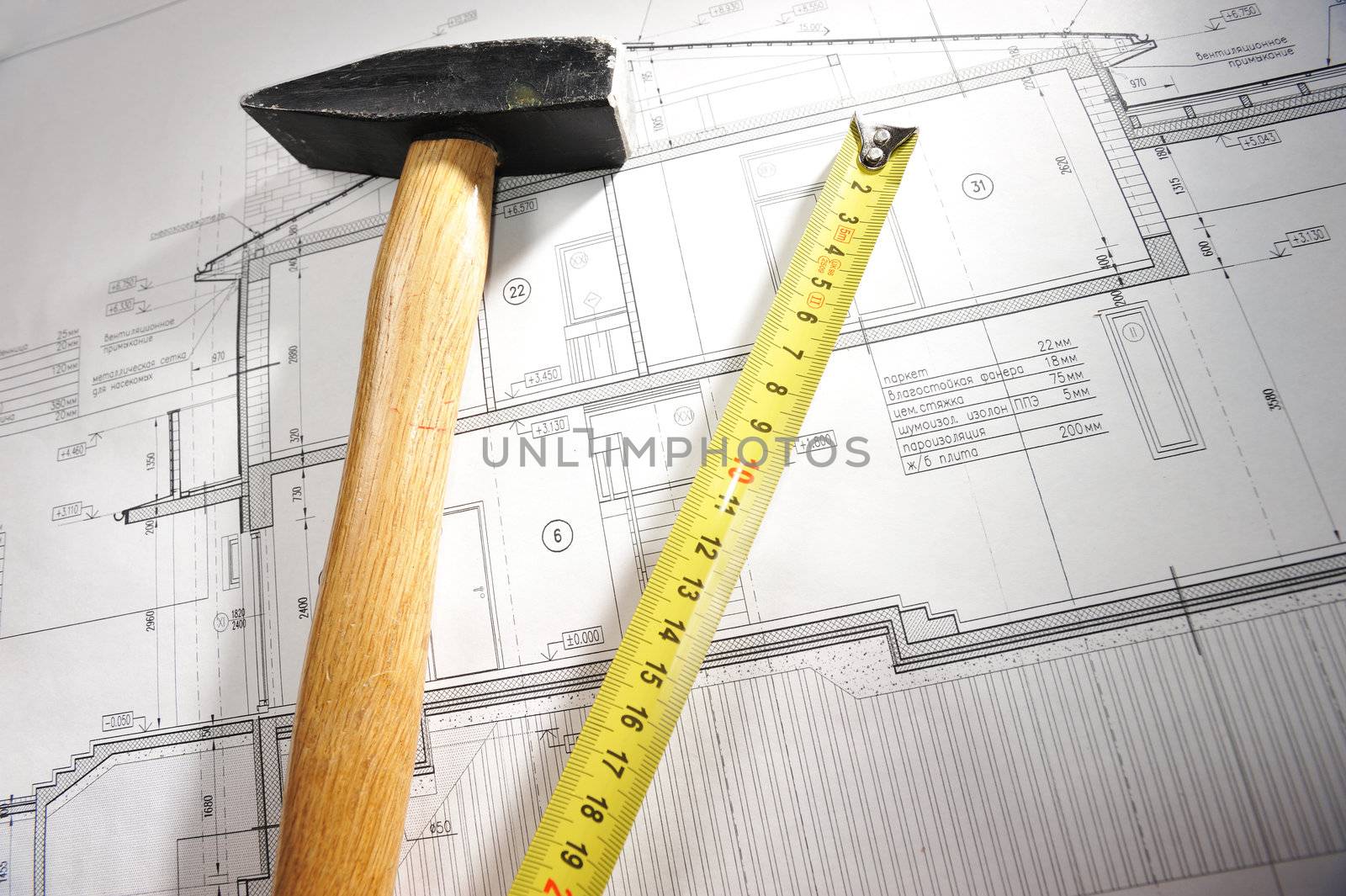 Hammer and measure tape over house plan blue prints