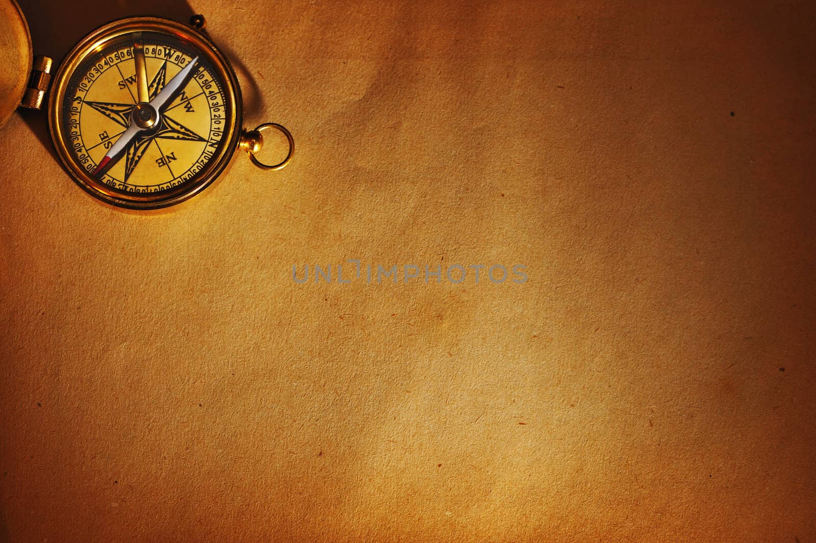 Antique brass compass over old paper background