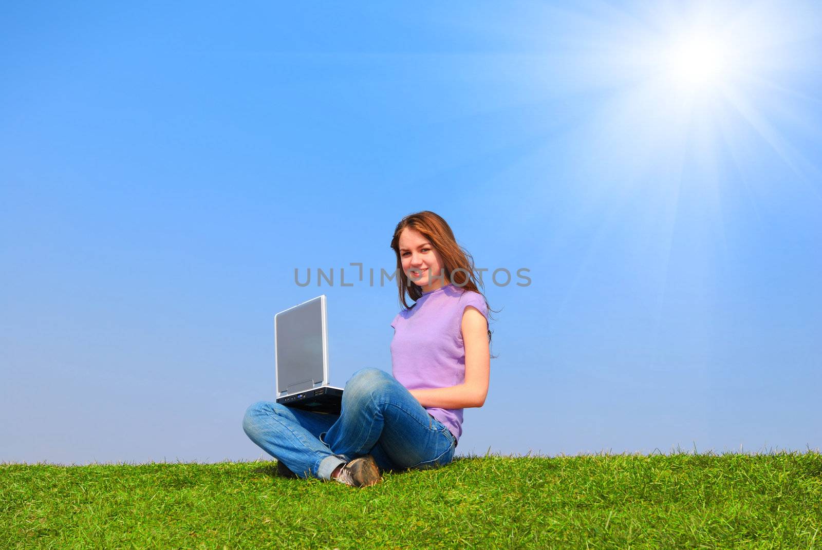 Girl with notebook sitting on grass against sky                                      