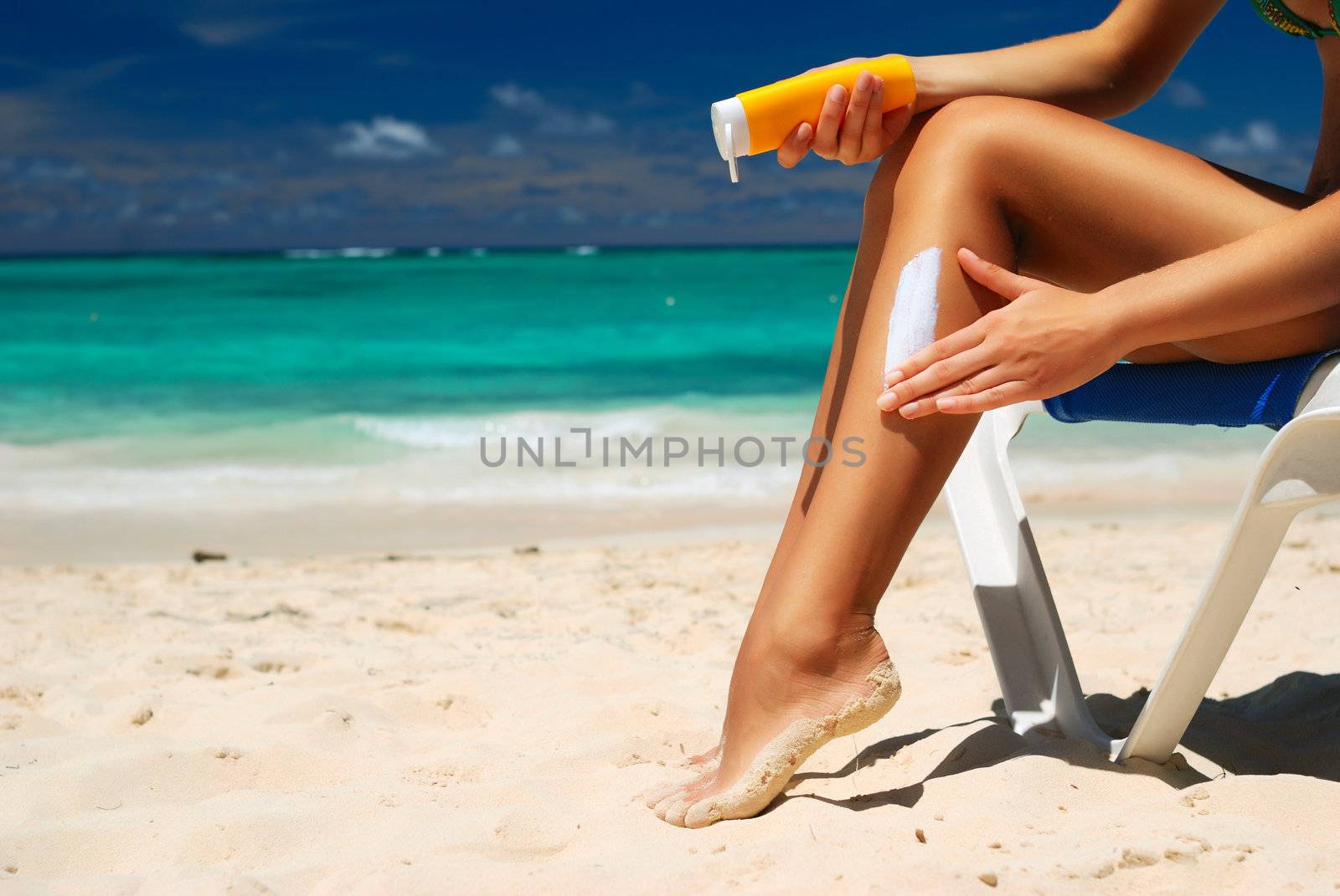 Tan woman applying sun protection lotion