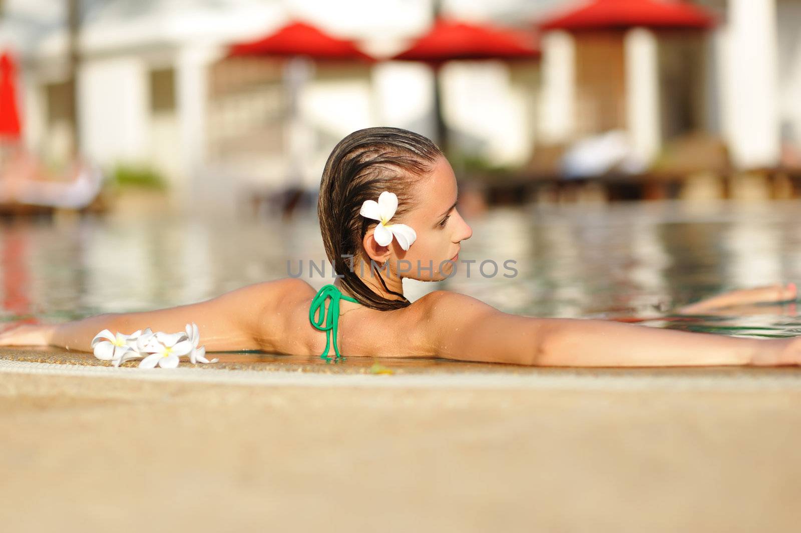 Girl in tropical swimming pool with flower in hairs