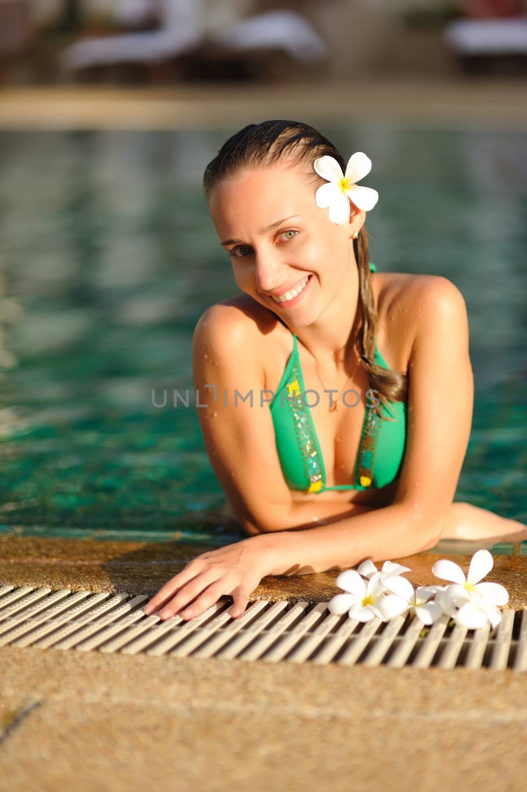 Girl in tropical swimming pool with flower in hairs