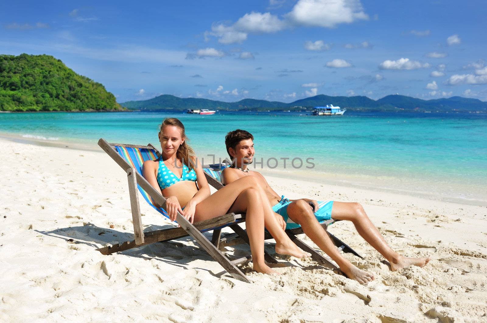 Couple on a tropical beach in chaise lounge