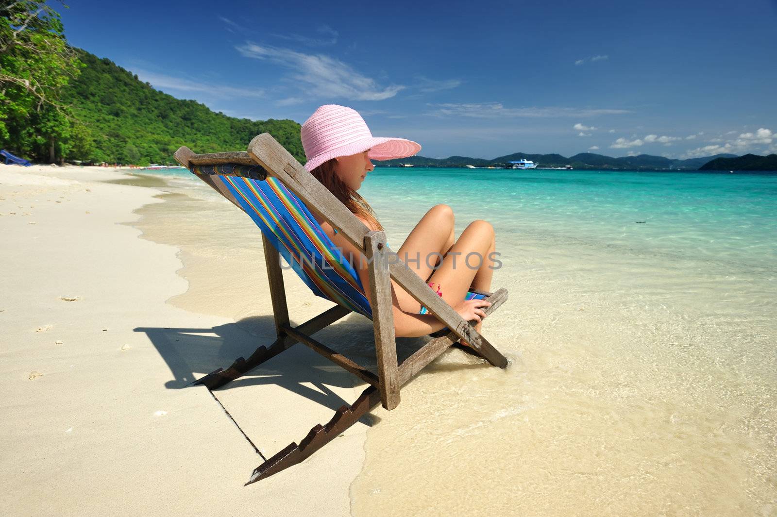 Girl on a tropical beach in chaise lounge