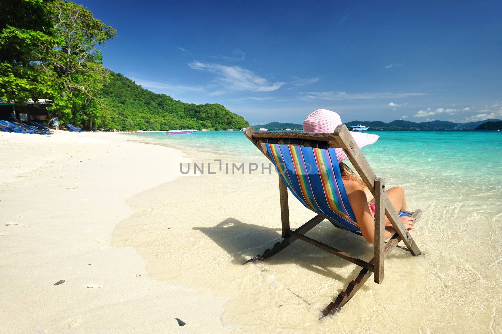 Girl on a tropical beach in chaise lounge