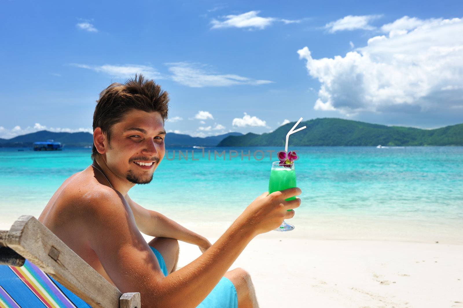 Man on a beach with cocktail