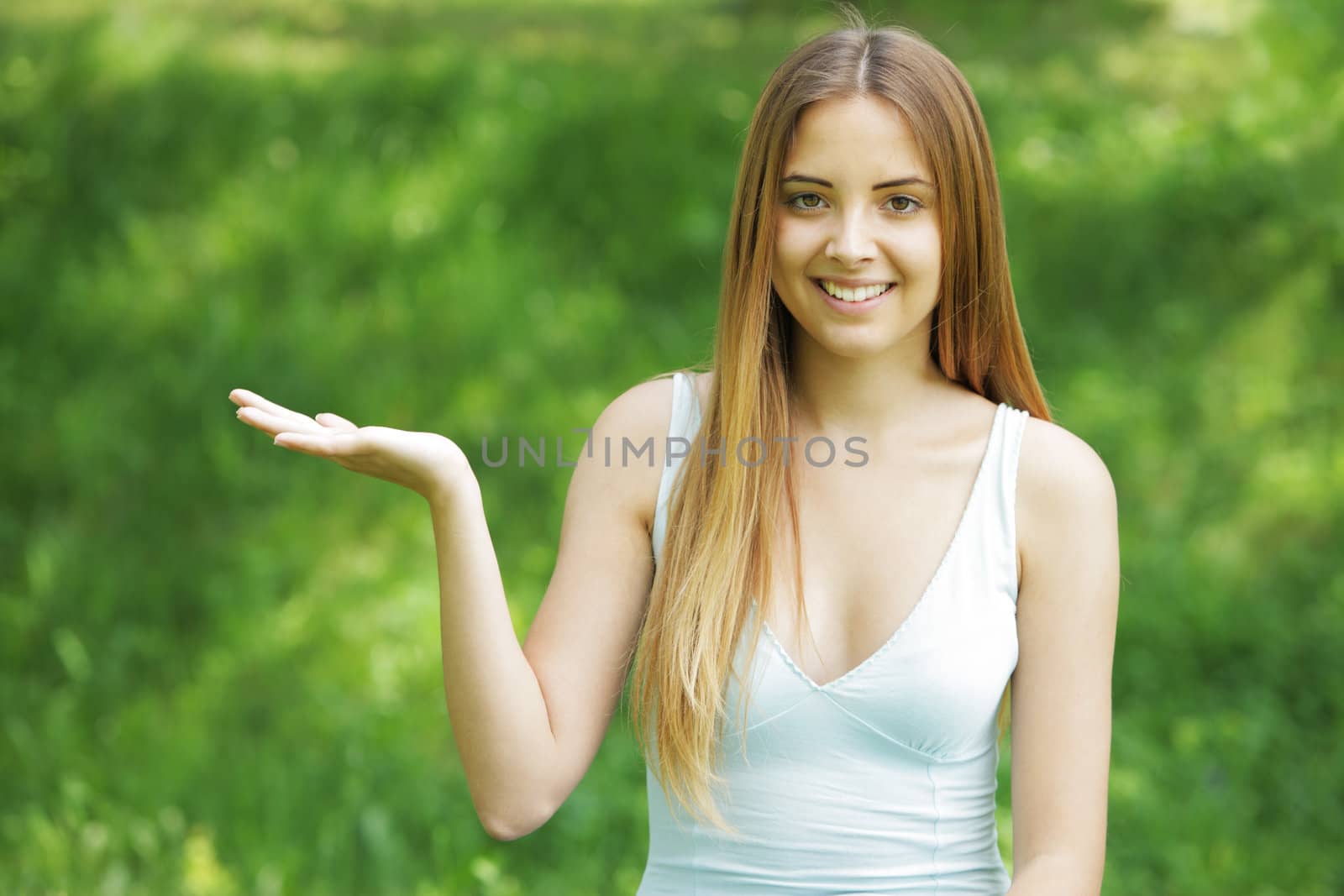 Smiling young woman pointing at copy space on green background