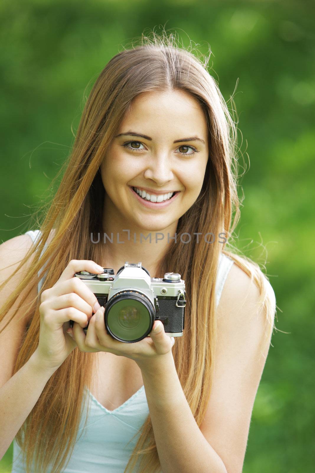 Portrait of beautiful smiling blonde girl , making photos at summer green park.