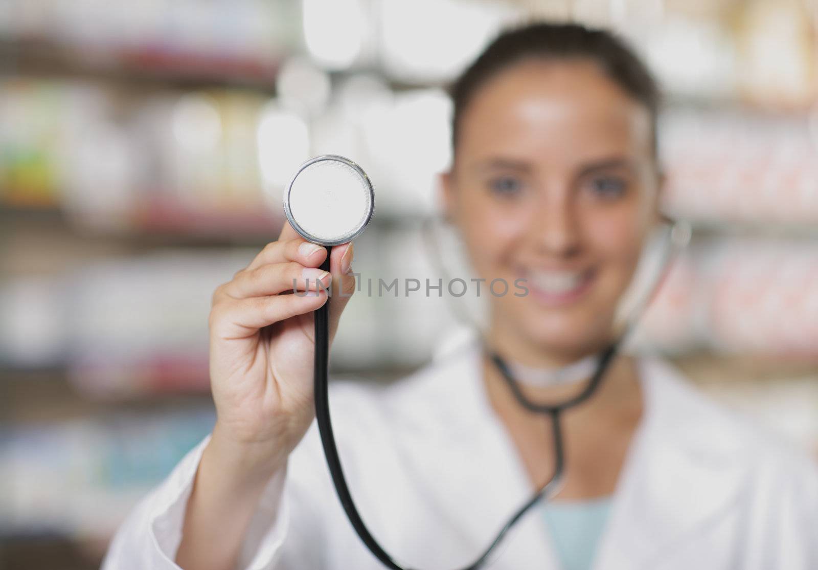 Young woman doctor holding stethoscope in pharmacy, shallow depth of field