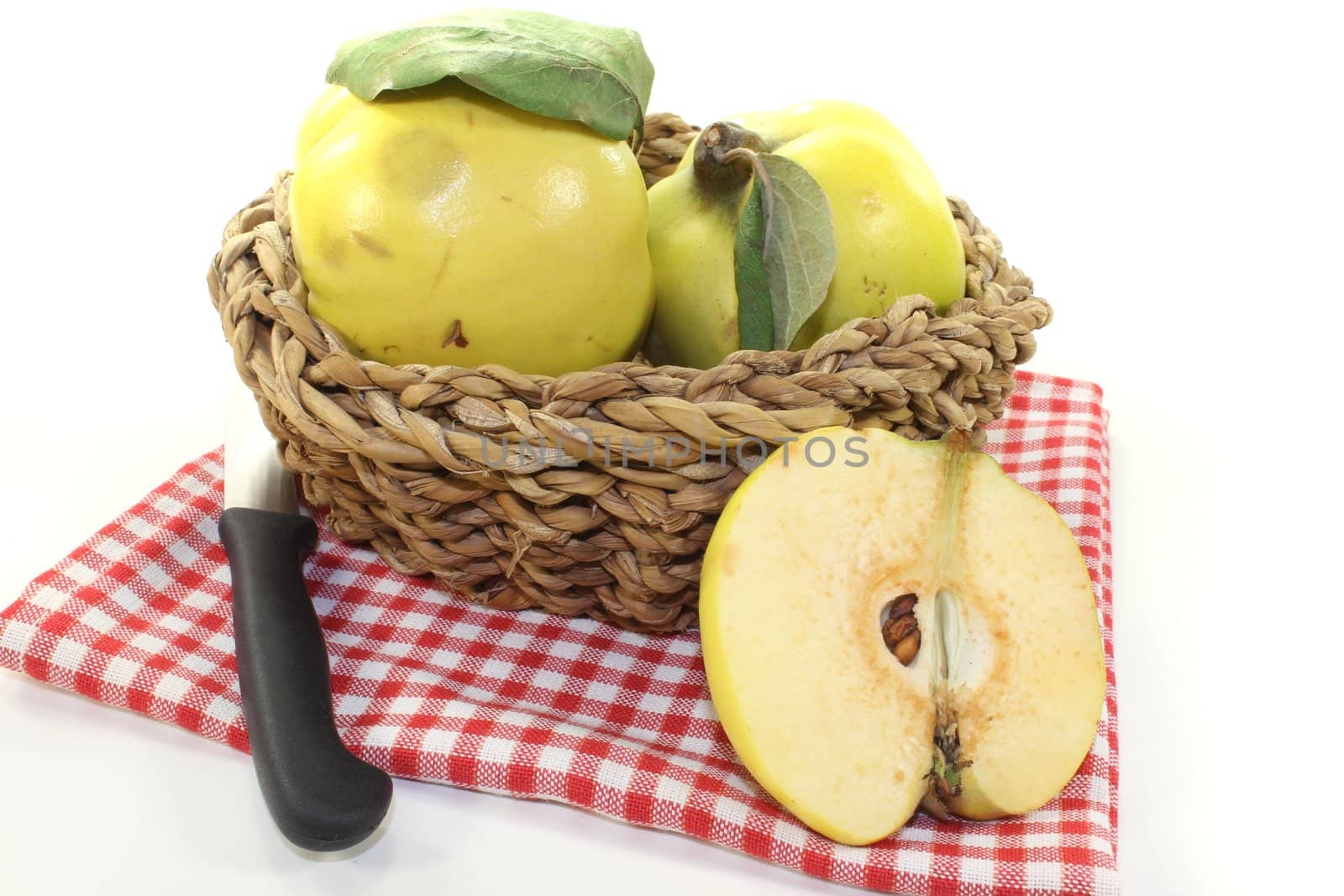 Quinces with leaves in a basket on a light background