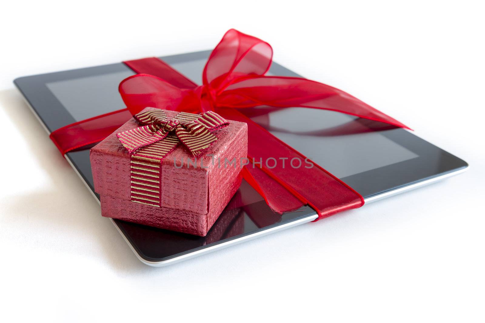 Digital tablet with red ribbon gift isolated on white.