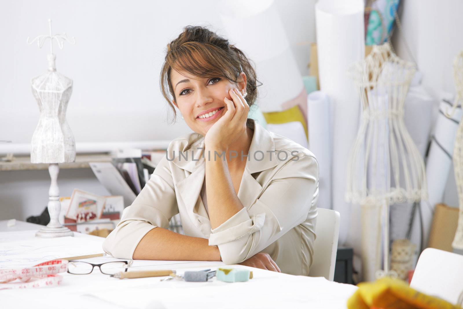 Smiling female fashion designer sitting at office desk
