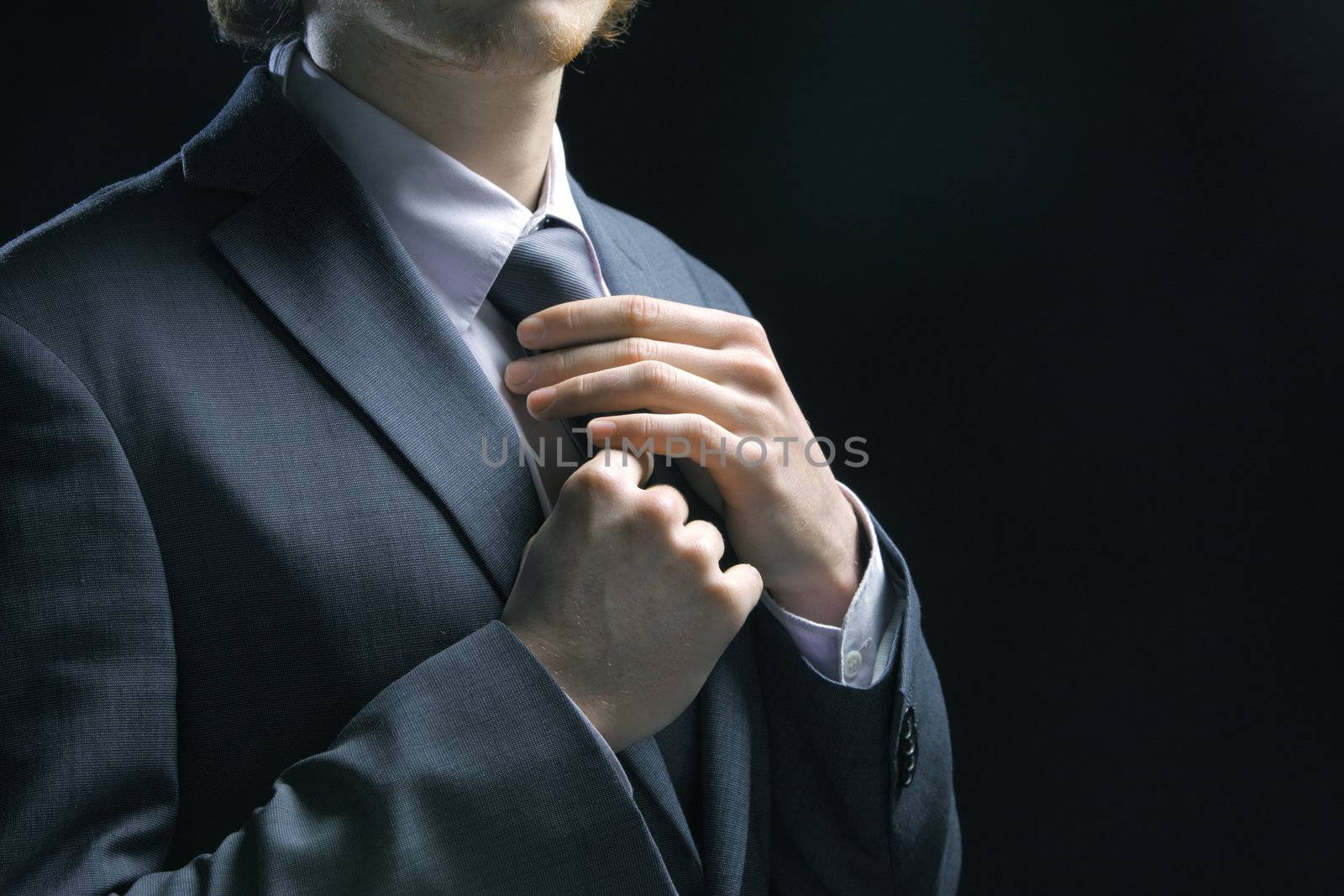 Business man adjusting tie by stokkete