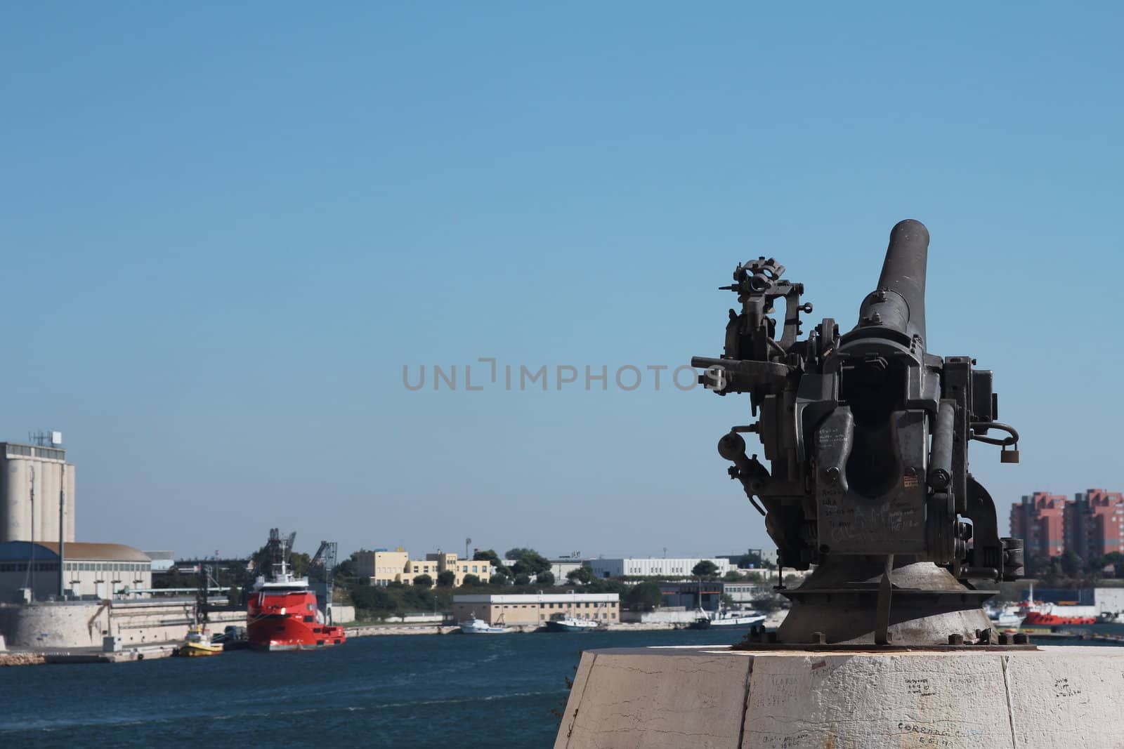 Old 30's cannon facing the port of Brindisi, with view of the port behind
