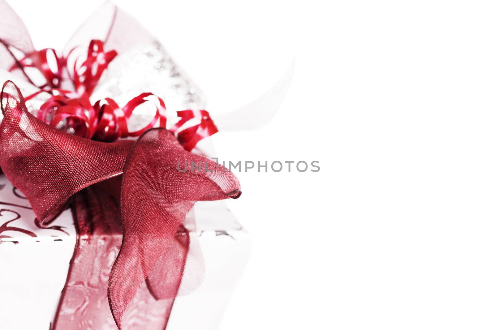closeup of a silver christmas present with red ribbons on white background