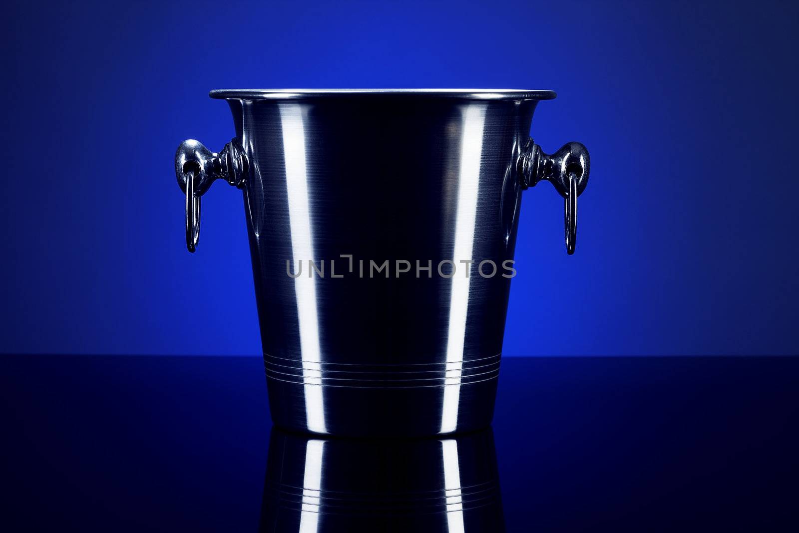 empty champagne bucket on a mirror with blue background