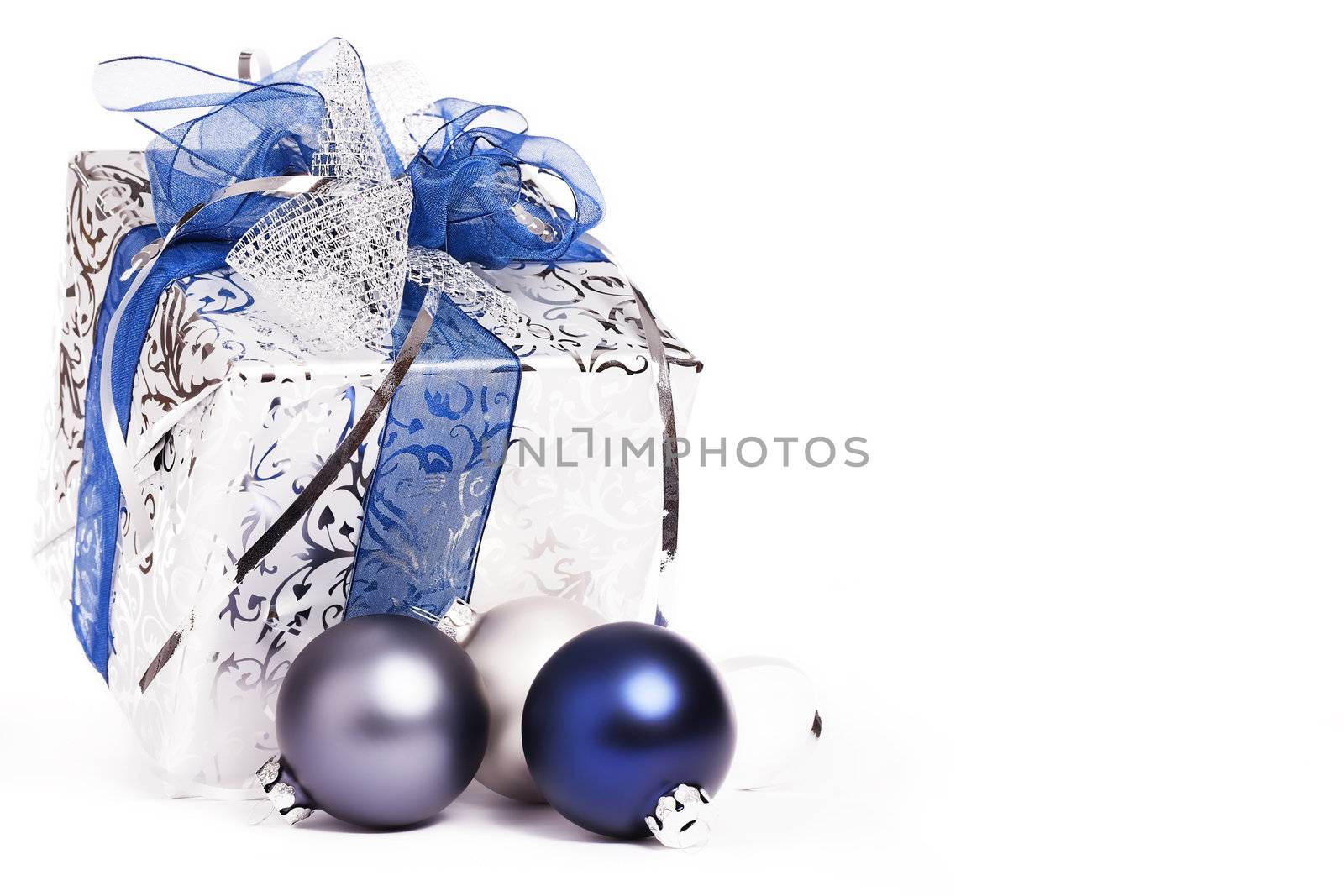 beautiful silver christmas present with blue ribbons and blue and silver christmas balls on white background