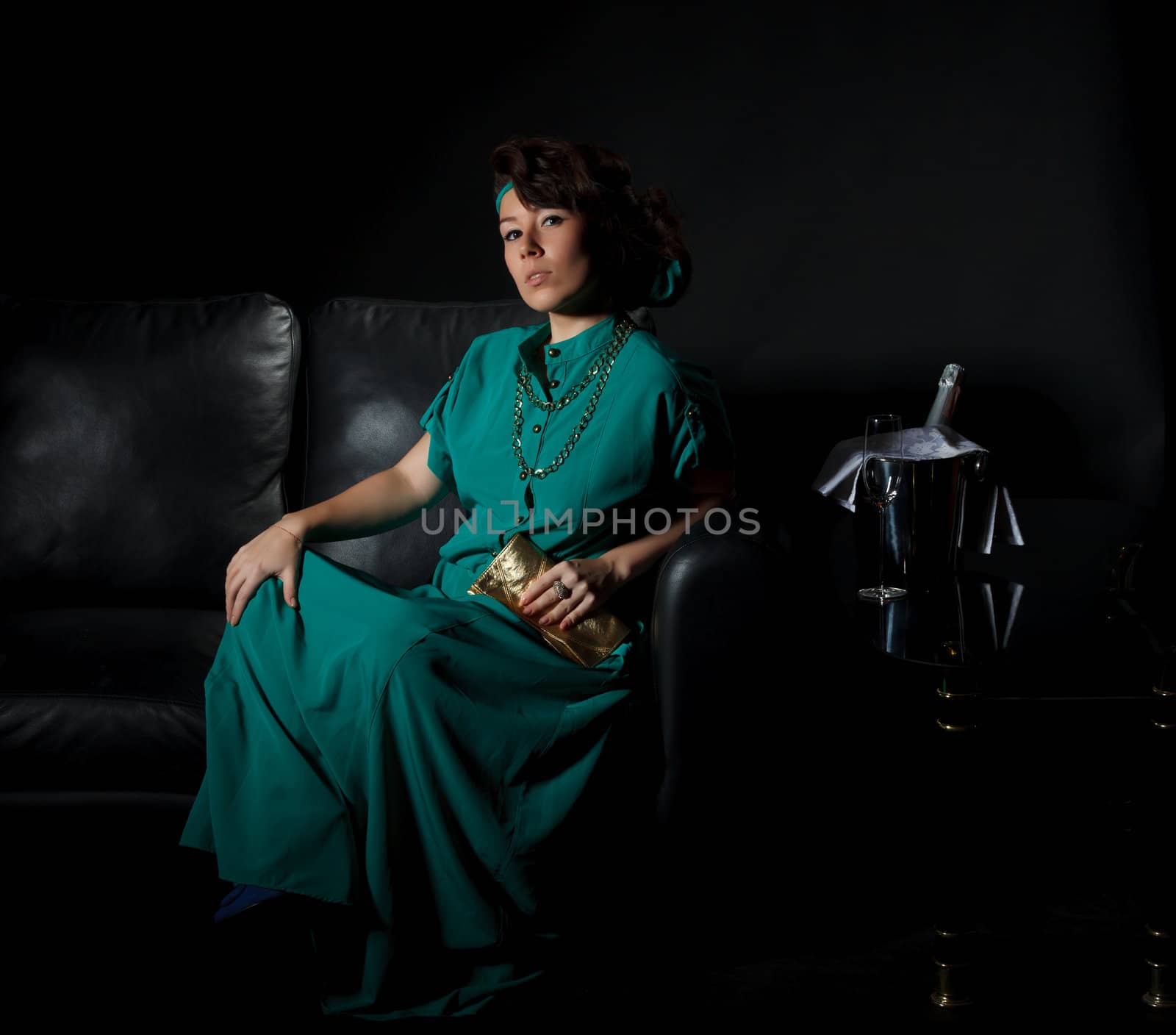 Beautiful girl sitting on a sofa, black background