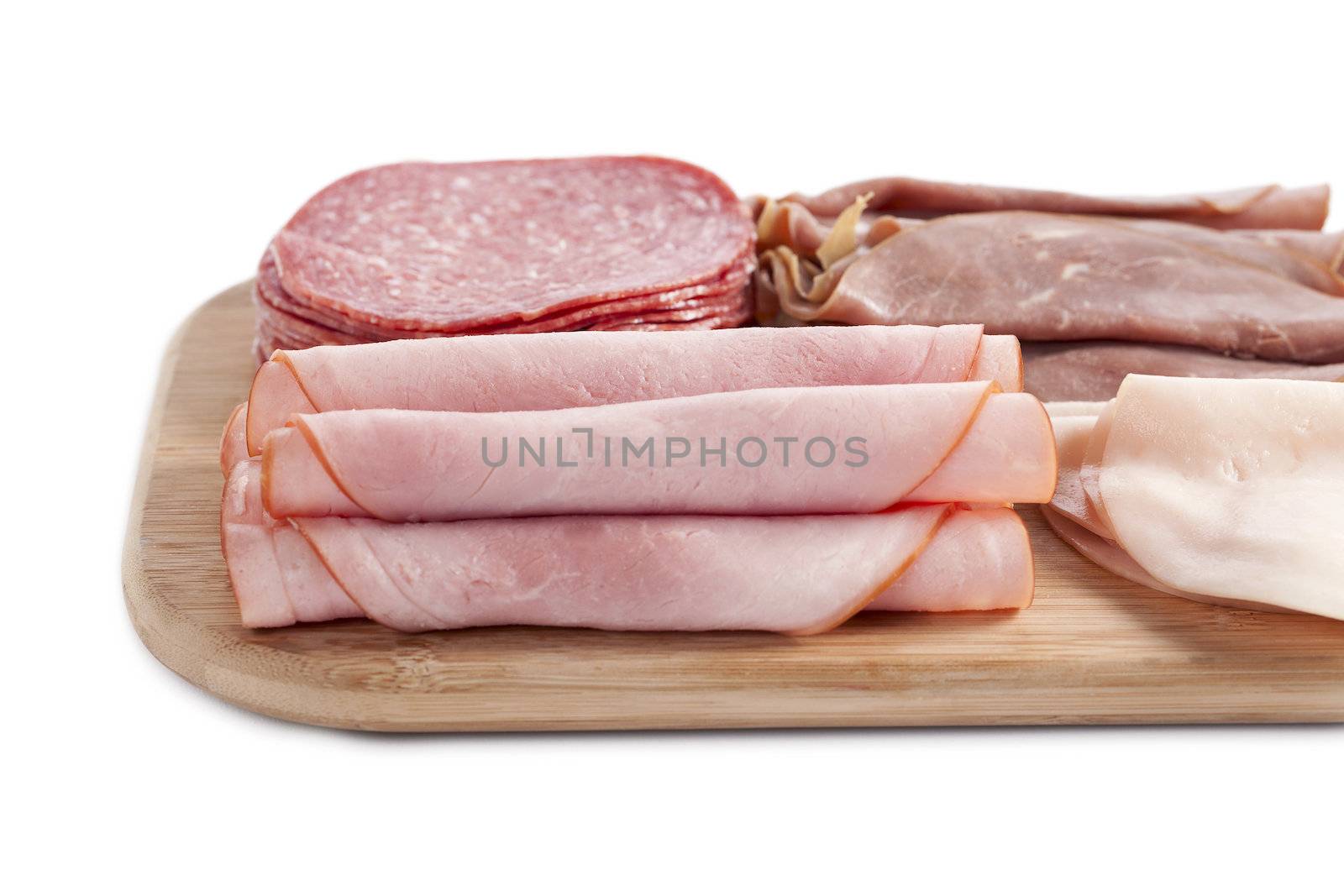 Close up image of ham in wooden plate against white background