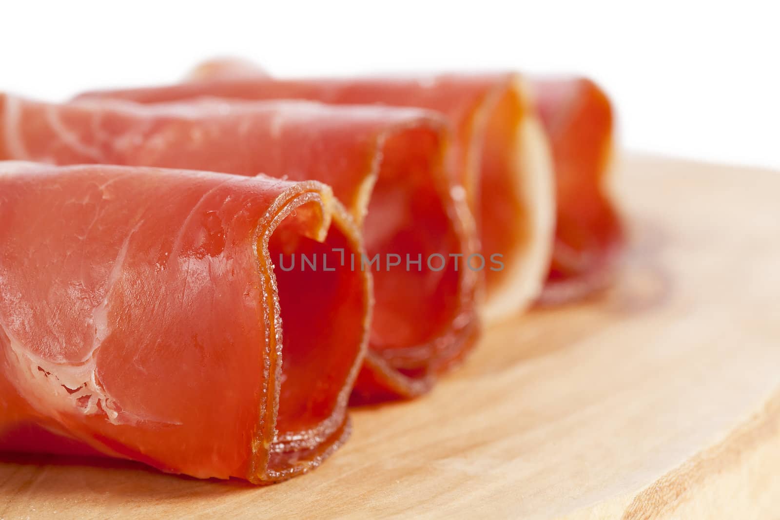 Macro shot into the ham rolled on the wooden board against the white background