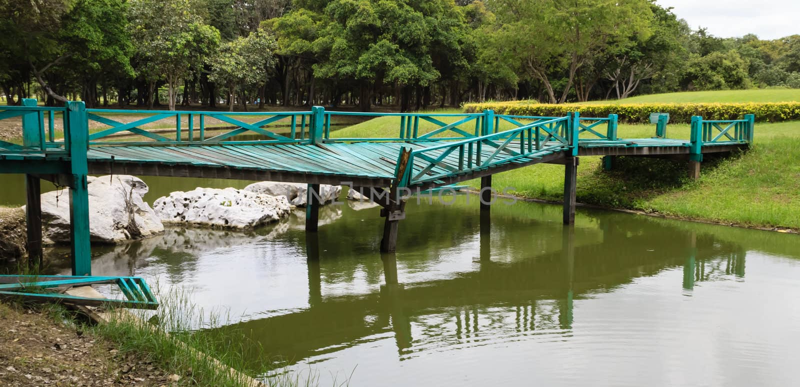 Old wooden green bridge collapses down the stream in the park.