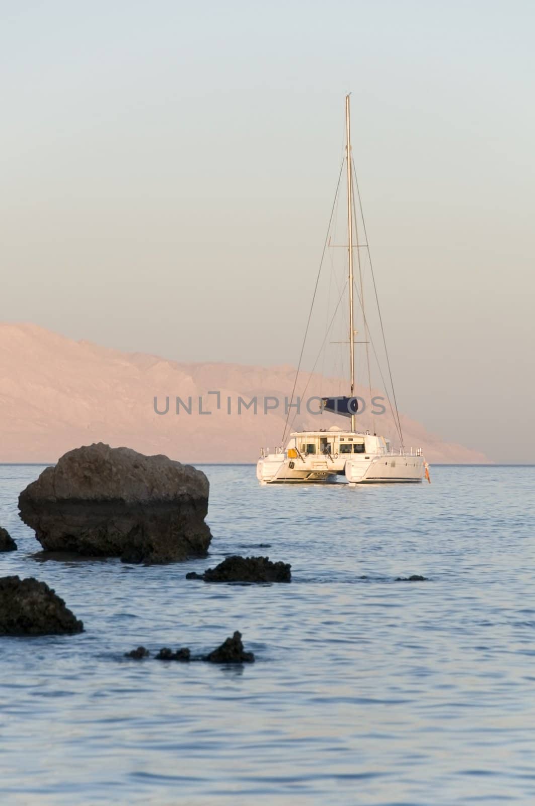 Nice catamaran yacht in beauty blue bay at sunset light