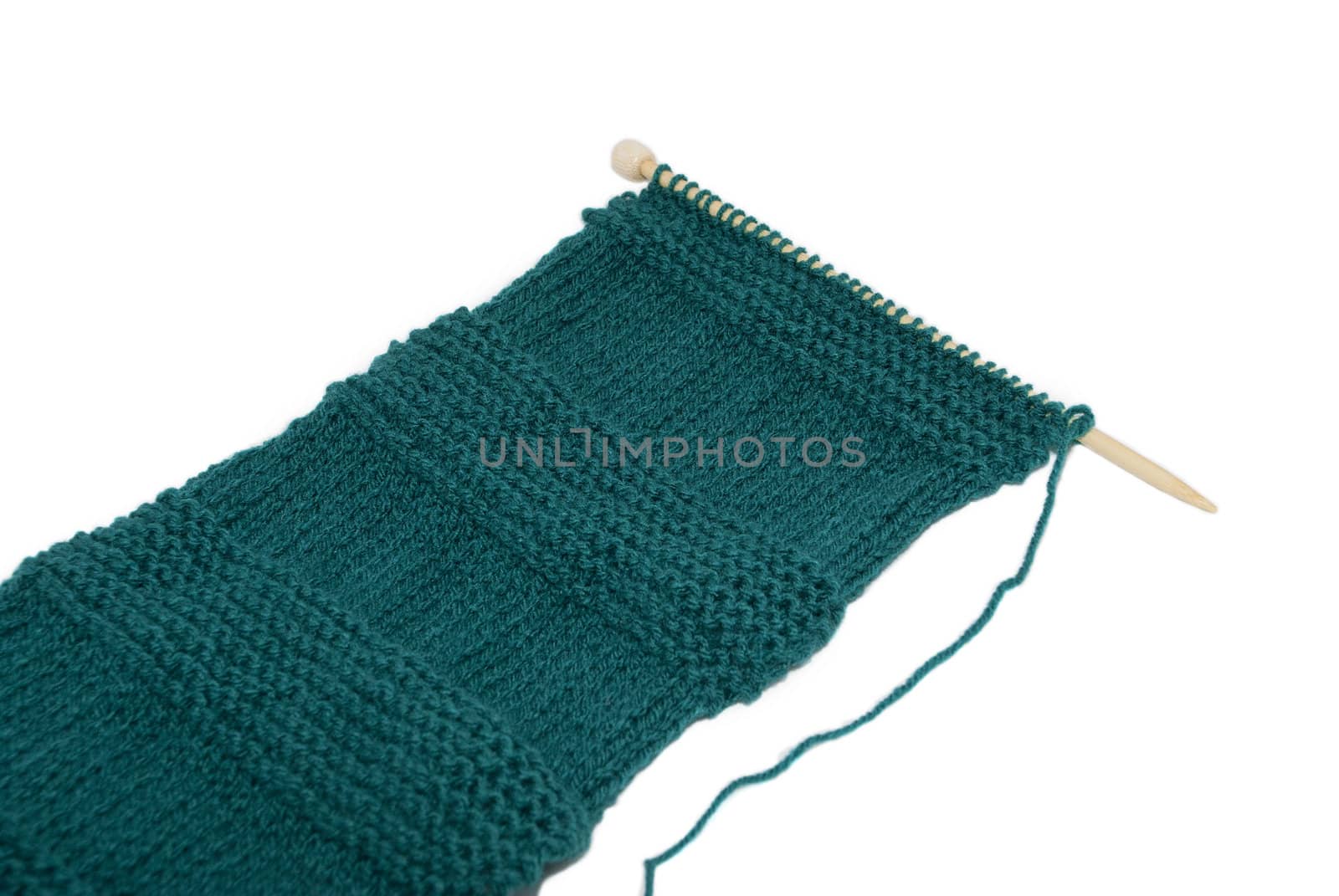 Unfinished scarf on knitting needle in stocking and garter stitch