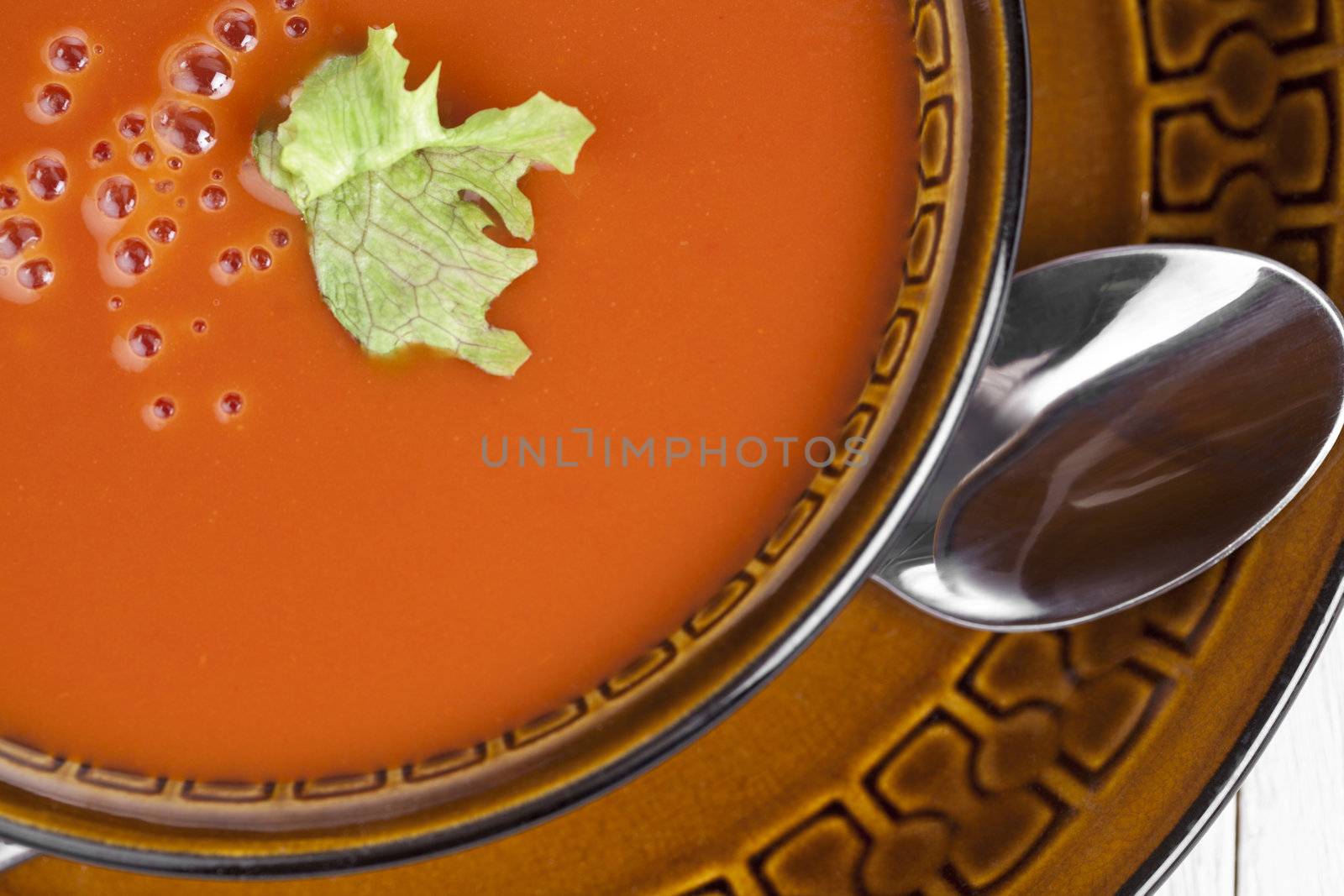 Tomato soup with green leaf garnish on a ceramic bowl