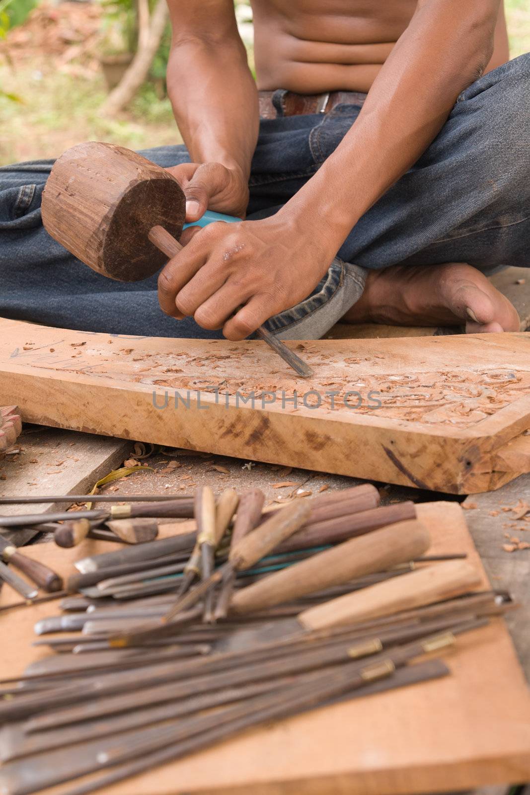 Traditional craftsman carving wood with Thai floral motifs