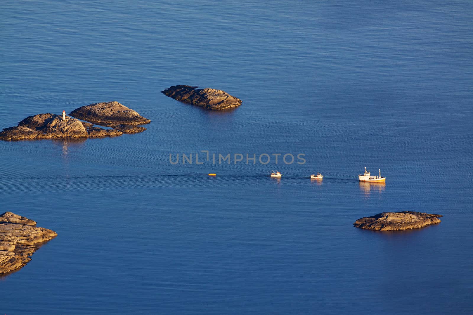 Bird eye view of fishing boats sailing between by rocky islets near Henningsvaer on Lofoten islands in Norway
