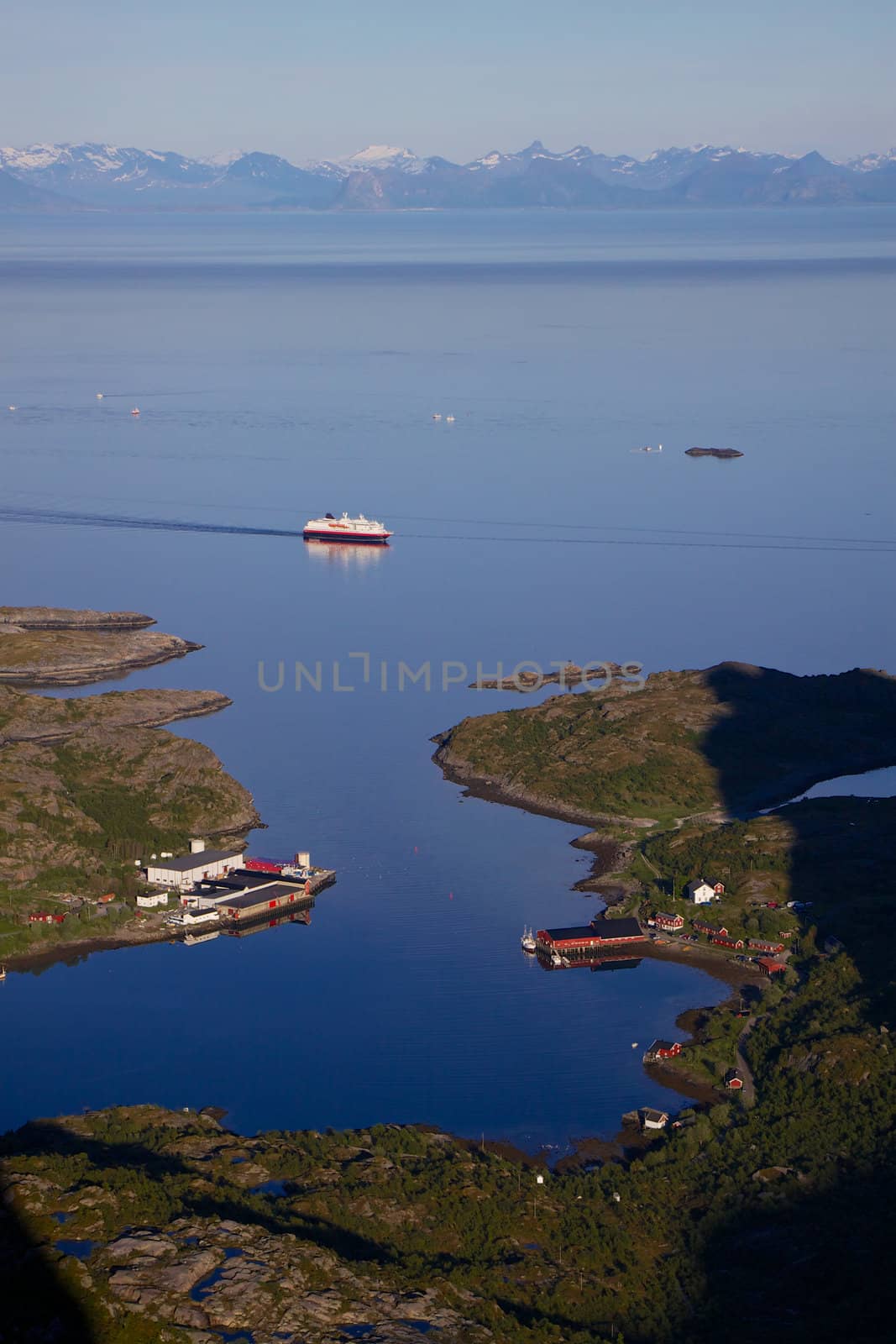 Norwegian cruise ship passing by fishing harbor in Kalle on Lofoten islands, Norway