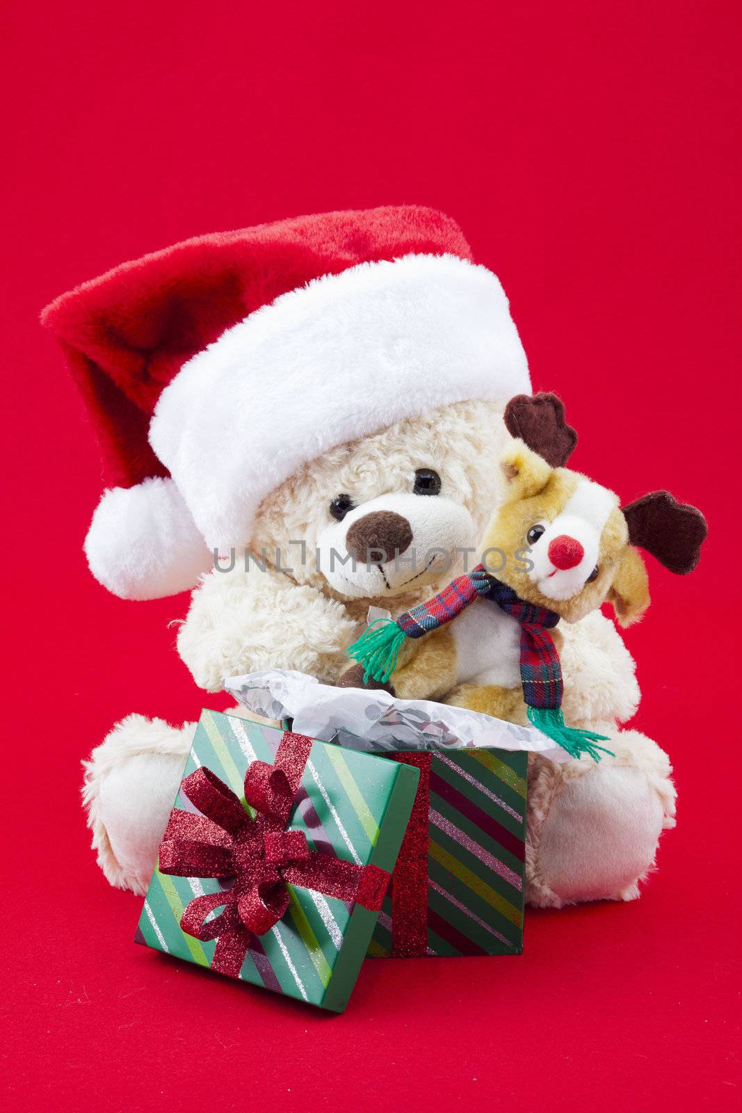 Festive themed toys sitting in front of a opened gift isolated on red.