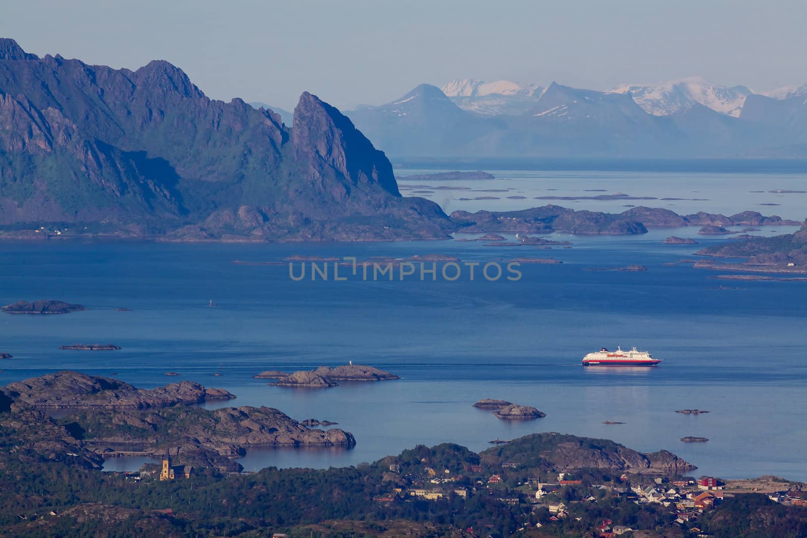 Large cruising ship leaving town of Svolvaer on Lofoten islands in norway with scenic panorama