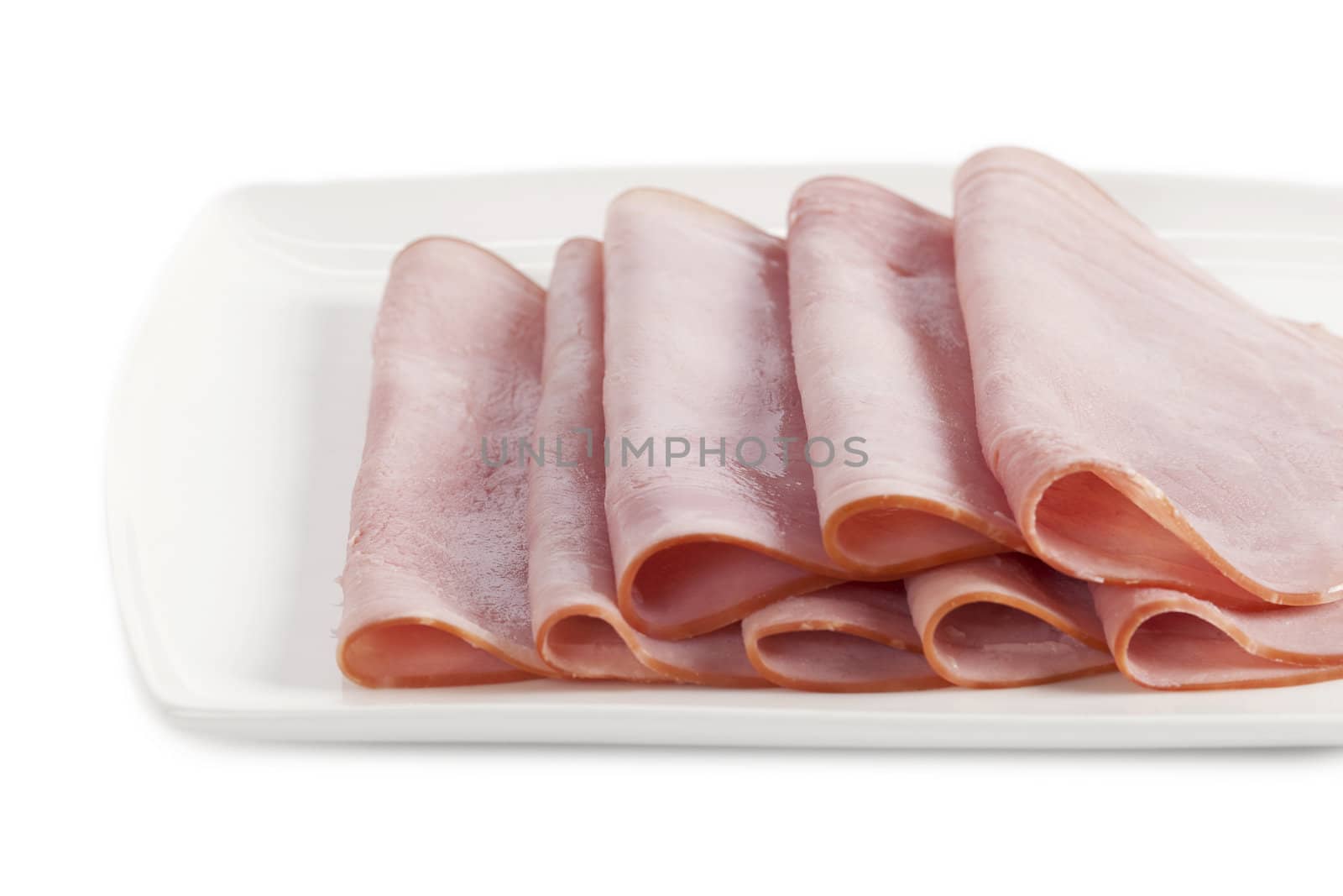 Close up image of slices of ham on white plate against white background