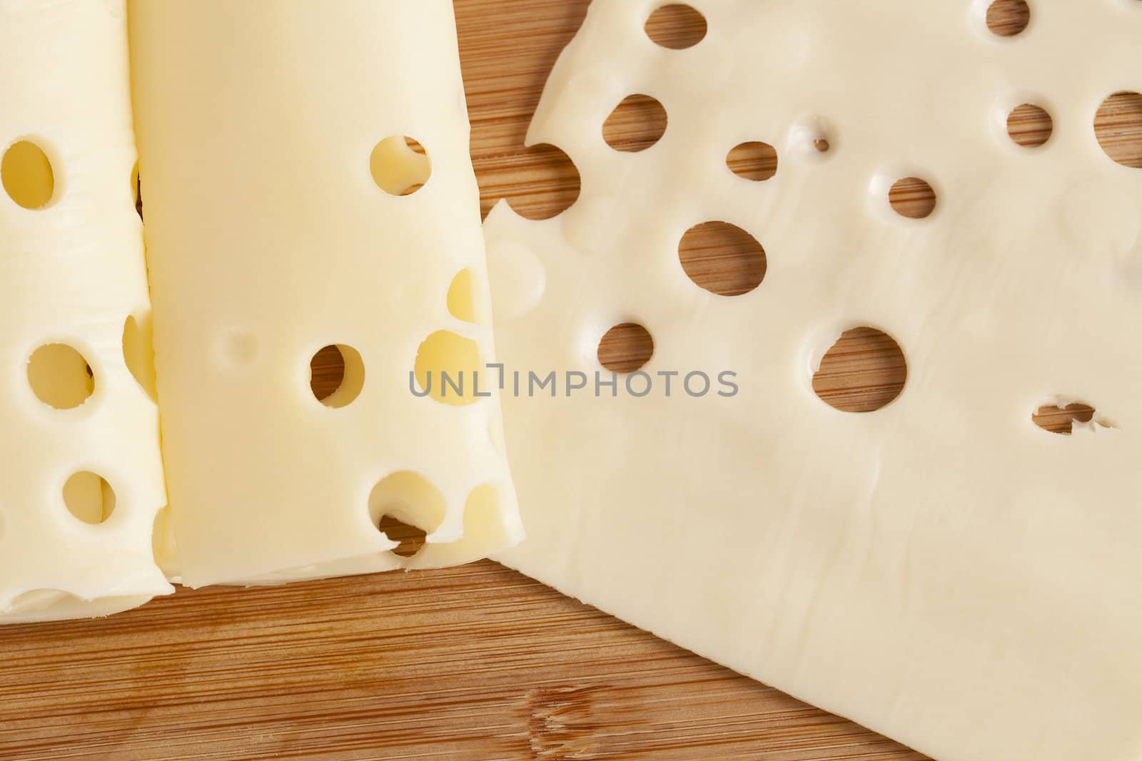 Thin slices of cheese over a wooden background