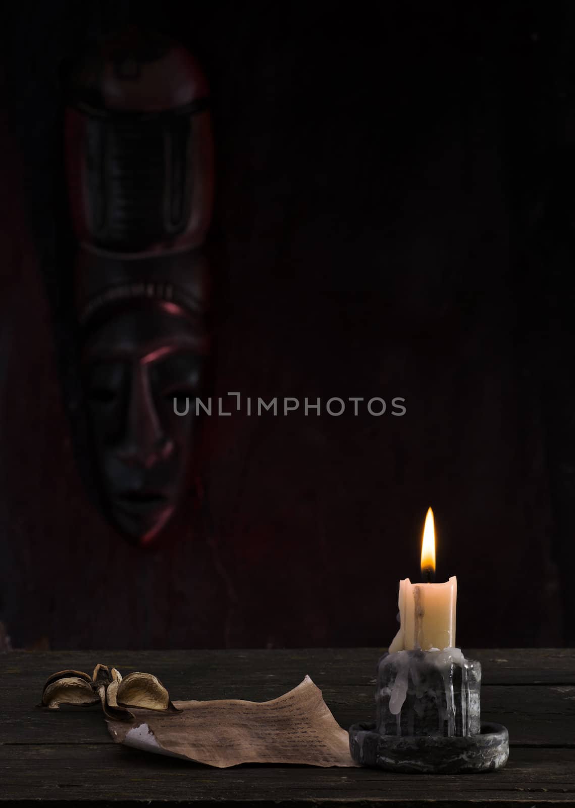 reading a letter by candlelight with an African mask